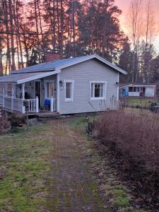 a white house with a porch and a yard at Peaceful riverside cottage with sauna in Myllykylä