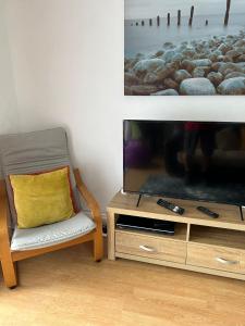 a chair with a yellow pillow sitting next to a tv at Affordable Saundersfoot Holidays in Pembrokeshire