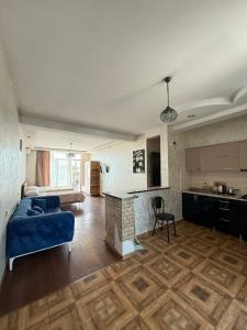 a living room with a blue couch and a kitchen at Hotel Arev Kobuleti in Kobuleti