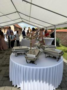 people standing under a white tent with machines on a table at Lovacka kuca Valenovac in FeriÄanci