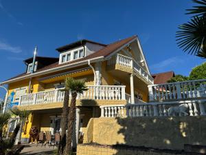 a yellow house with a balcony and a dog on the porch at Casa Kovacs in Herbolzheim