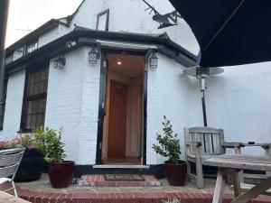 a white brick house with a door and a bench at Plough inn in Great Mongeham
