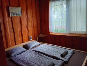 a bedroom with a bed with two pillows and a window at Atpūtas vieta- Mini ZOO BUKI in Vārve