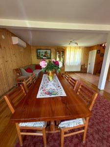 a living room with a wooden table with flowers on it at Casa de Vacanță Haneș - Private Cabin - Orchard & Mountain Views - Transalpina & viaTransilvanica in Pianu de Sus