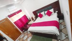 a bedroom with a bed with red and white pillows at Bluemoon Stay in Uttarkāshi