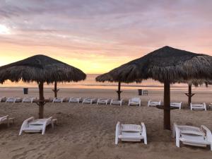 a group of chairs and umbrellas on a beach at Sandy Beach Princesa B309 Ocean Front Resort in Puerto Peñasco +35 photos