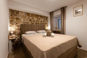a bedroom with a large bed with a stone wall at Apartmani Žunić in Pag