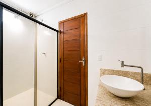 a bathroom with a sink and a wooden door at Pousada Miriam in Limeira