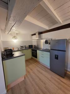 a large kitchen with a refrigerator and a counter at L'Écrin Historique - Duplex - Vieux Chaumont in Chaumont