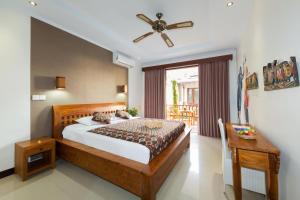 a bedroom with a bed and a ceiling fan at Sandat Bali Ubud in Ubud