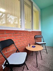 two chairs and a table in front of a brick wall at Apartman Ditta in Subotica