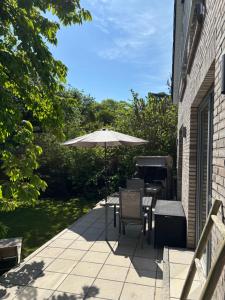 a patio with an umbrella and chairs and a grill at Im Bademantel an den Strand - mit Terrasse in Eckernförde