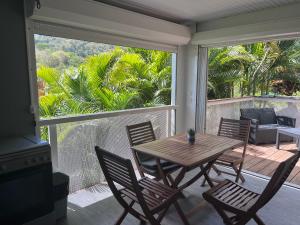 a porch with a wooden table and chairs on a balcony at Villas smoothie SYCARO in Le François
