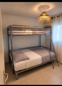 two bunk beds in a room with a chandelier at Vacances détente in Canet-en-Roussillon