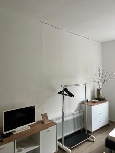 a living room with a white wall with a tv and a desk at charmant studio in Le Bugue
