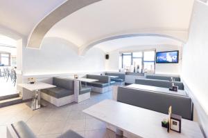 a restaurant with couches and tables and a tv at Hotel Bacco in Beinette