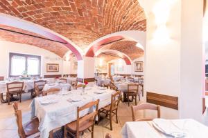 a restaurant with white tables and chairs and a brick ceiling at Hotel Bacco in Beinette