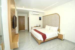 a bedroom with a bed and a flat screen tv at UK Plaza in Edappāl