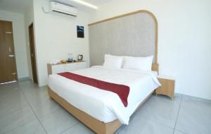 a bedroom with a large white bed with a large headboard at UK Plaza in Edappāl