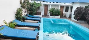a row of blue chairs next to a house with a swimming pool at primavera jambiani in Mfumbwi