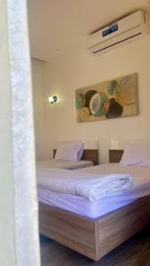 a bedroom with two beds and a painting on the wall at شالية الشفق in Al ‘Aqar