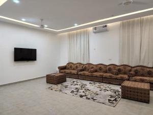 a living room with a couch and a flat screen tv at شالية الشفق in Al ‘Aqar