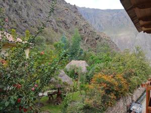 a view of a mountain with flowers and trees at Pinkuylluna Lodge in Ollantaytambo