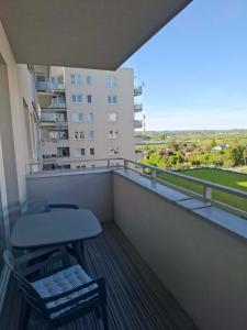 a chair and stool on a balcony with a building at Apartament Rekiny na Wakacjach - Aquapark Reda 200m - Prywatny Parking in Reda