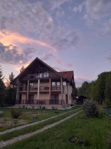 a house on a hill with a sunset in the background at Cabana Andrea in Arpaşu de Sus