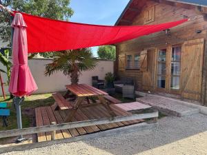 a red umbrella and a picnic table in front of a cabin at " domaine des chevrettes chalet cosy au cœur des châteaux " in Cour-Cheverny