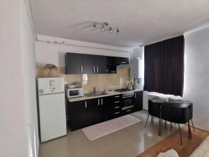 a kitchen with black and white appliances and a table at Flower Apartment in Floreşti