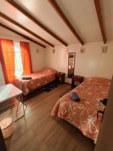 a bedroom with two beds and a table and a window at Kramm House Aldea 47 in Coihaique