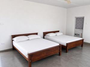 two beds in a room with white walls at Villa Ocean Gift in Galle