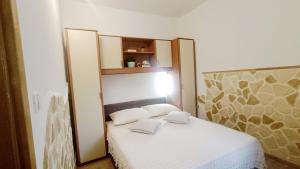 a small bedroom with a white bed with two pillows at Apartment Igralište Mirakul in Seget Vranjica +47 photos