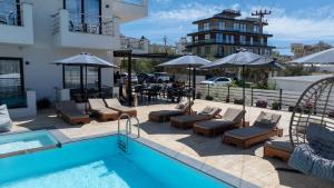 a pool with chairs and umbrellas next to a building at Noa Boutique Hotel in Ksamil