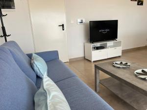 a living room with a blue couch and a tv at Pergola Penthouse Xaghra in Xagħra
