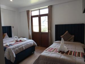 a bedroom with two beds and a window at Pinkuylluna Lodge in Ollantaytambo