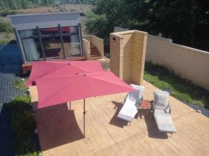 a pink umbrella sitting on a patio with two chairs at solar eclipse house in Husillos