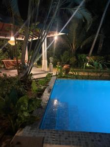 a blue swimming pool in a resort at night at All View Resort in Tangalle