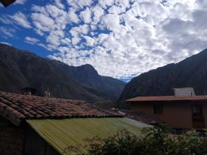 a view of a valley with mountains and a house at Pinkuylluna Lodge in Ollantaytambo