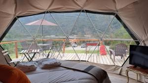 a tent with a view of a deck with a bed at Alma Lemu Lodge in Los Ladrillos