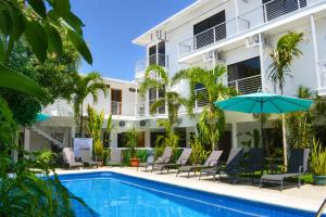 a pool in front of a building with chairs and an umbrella at Wide Mouth Frog Quepos in Manuel Antonio
