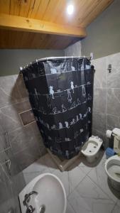 a bathroom with a shower curtain with a toilet and a sink at Cabaña Arashi in Tafí del Valle
