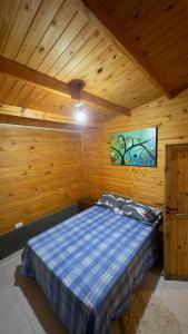 a bedroom with a bed in a wooden cabin at Cabaña Arashi in Tafí del Valle