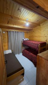 a room with two beds in a wooden cabin at Cabaña Arashi in Tafí del Valle