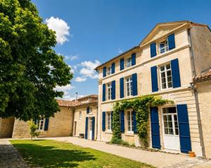 an old house with blue shutters and a yard at Maison d'Hôtes Le Clos de Bacchus in Julienne