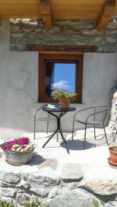 a patio with two chairs and a table with flowers at La cò viéyi - La casa vecchia in Ala di Stura