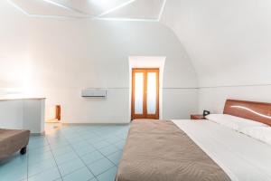 a white room with a bed and a kitchen at Chill House mare bus e servizi a piedi in Procida