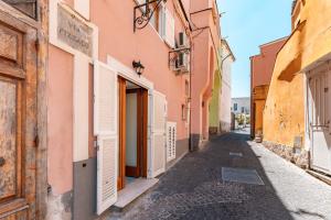an alley in an old town with pink and yellow buildings at Chill House mare bus e servizi a piedi in Procida