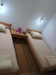 two twin beds in a room with a table at Šarganska Idila in Mokra Gora +64 photos